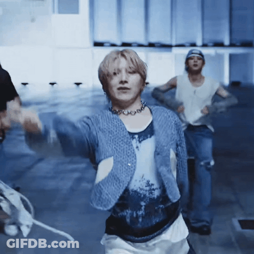 A Man In A Blue Sweater Is Dancing In A Room . GIF