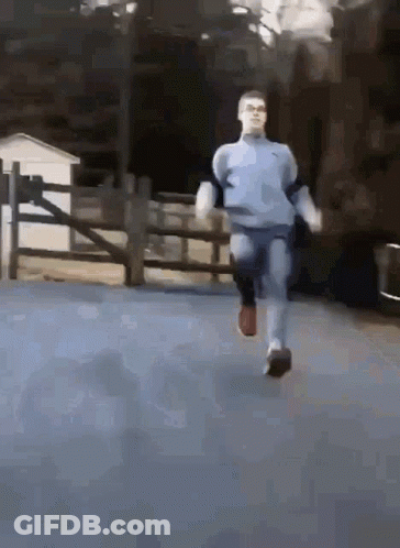 A Man In A Blue Sweater Is Running Down A Road GIF