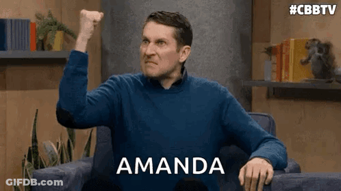 A Man In A Blue Sweater Is Sitting In A Chair With His Fist In The Air And The Word Amanda Behind Him . GIF