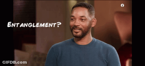 A Man In A Blue Sweater Is Smiling With The Words " Entanglement " Below Him GIF