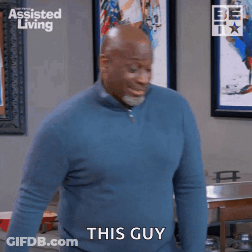 A Man In A Blue Sweater Is Standing In A Kitchen And Saying This Guy GIF