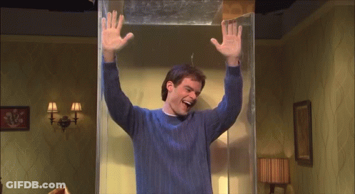 A Man In A Blue Sweater Is Standing In A Room With His Arms Up GIF