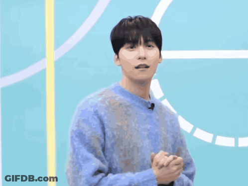 A Man In A Blue Sweater Is Standing In Front Of A Blue Background GIF