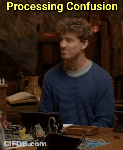 A Man In A Blue Sweater Sits At A Table With Processing Confusion Written On The Bottom GIF