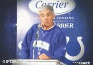 A Man In A Blue Sweater Stands At A Podium In Front Of A Carrier Logo GIF