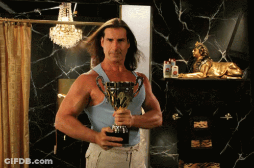 A Man In A Blue Tank Top Holds A Trophy That Says " Winner " On It GIF