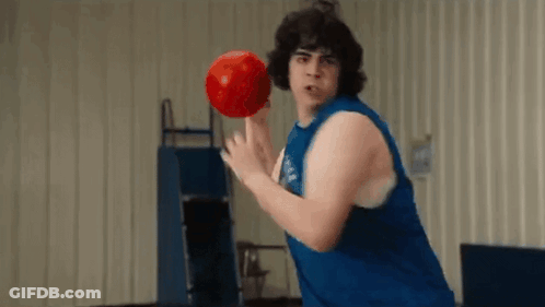 A Man In A Blue Tank Top Is Holding A Red Bowling Ball . GIF