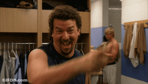 A Man In A Blue Tank Top Is Laughing In A Dressing Room GIF