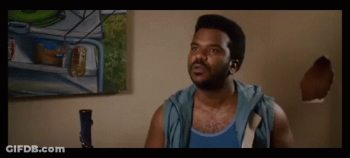 A Man In A Blue Tank Top Is Standing In Front Of A Painting On A Wall GIF