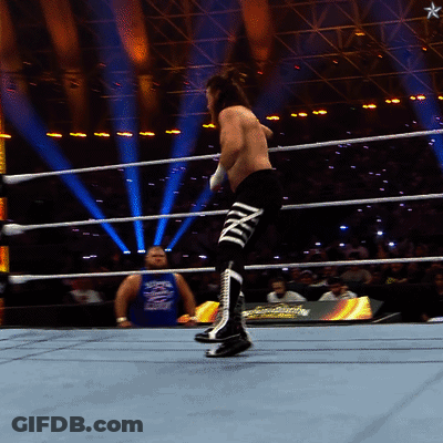 A Man In A Blue Tank Top With The Word Smackdown On It Stands In A Wrestling Ring GIF