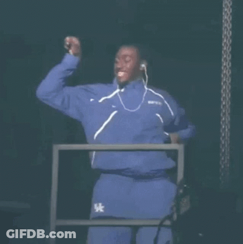 A Man In A Blue Tracksuit Is Dancing On A Stage . GIF