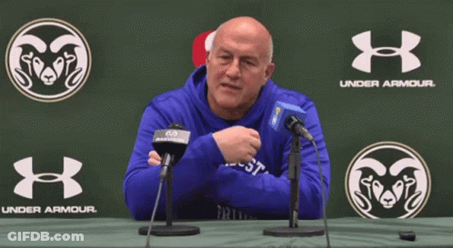 A Man In A Blue Under Armour Sweatshirt Is Sitting At A Table GIF
