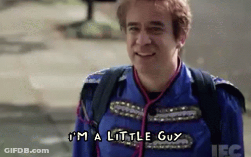 A Man In A Blue Uniform Is Smiling And Saying `` I 'M A Little Guy '' While Walking Down The Street . GIF
