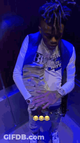 A Man In A Blue Vest Is Holding A Stack Of Money In His Hands . GIF