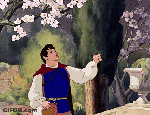 A Man In A Blue Vest Is Looking Up At A Tree GIF