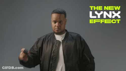 A Man In A Bomber Jacket Is Standing In Front Of A Sign That Says The New Lynx Effect GIF