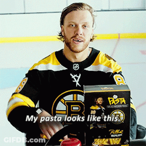A Man In A Boston Bruins Jersey Is Sitting In Front Of A Box Of Pasta GIF