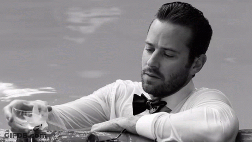 A Man In A Bow Tie Is Holding A Glass GIF