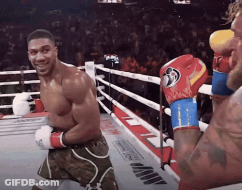 A Man In A Boxing Ring Wearing A Pair Of Boxing Gloves With A Flame Pattern GIF