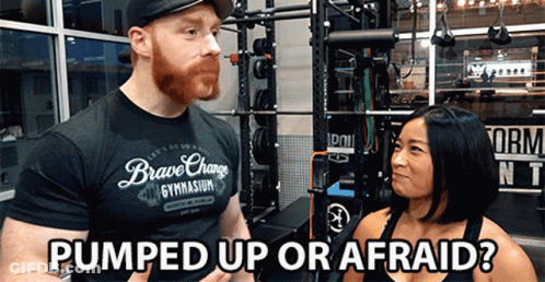 A Man In A Brave Change Gym Shirt Talks To A Woman In A Gym GIF