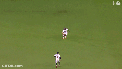 A Man In A Braves Jersey Sits On The Grass Stretching His Legs GIF