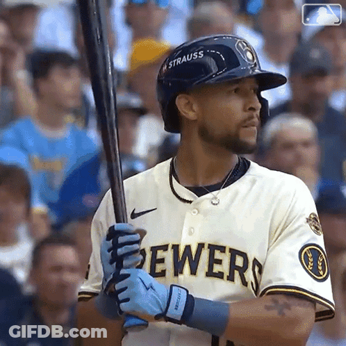A Man In A Brewers Jersey Is Holding A Baseball Bat . GIF