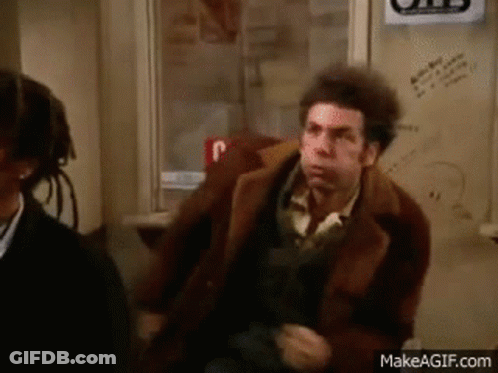 A Man In A Brown Coat Is Sitting Next To A Woman In A Chair . GIF