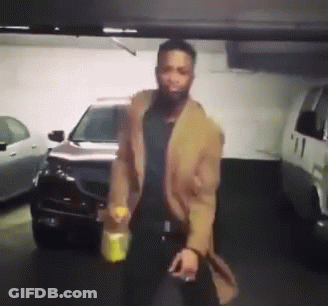 A Man In A Brown Coat Is Standing In Front Of A Car In A Parking Garage GIF