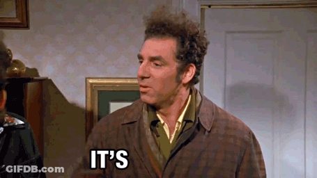 A Man In A Brown Coat Is Standing In Front Of A Door With The Words `` It 'S '' Written On It . GIF