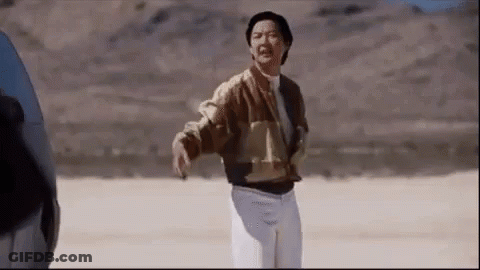 A Man In A Brown Jacket And White Pants Is Standing In A Desert . GIF