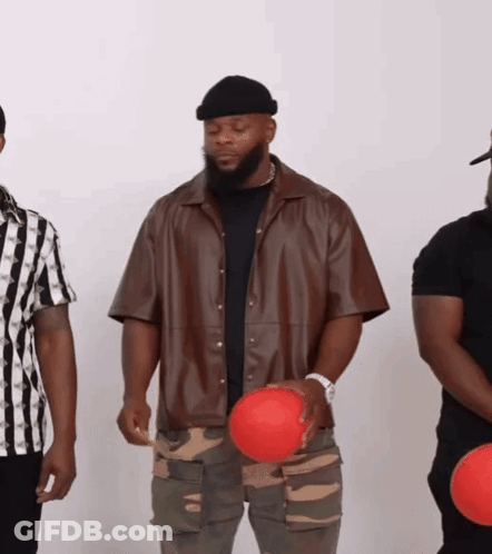A Man In A Brown Jacket Holds A Red Ball In His Hand GIF