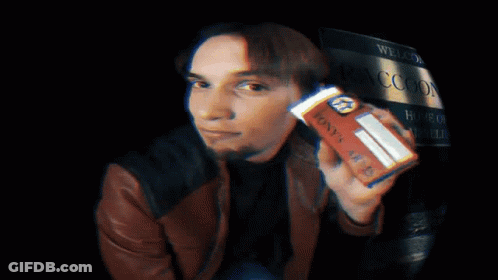A Man In A Brown Jacket Holds Up A Can Of Coca Cola GIF