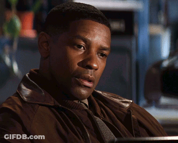 A Man In A Brown Jacket Is Sitting At A Desk GIF