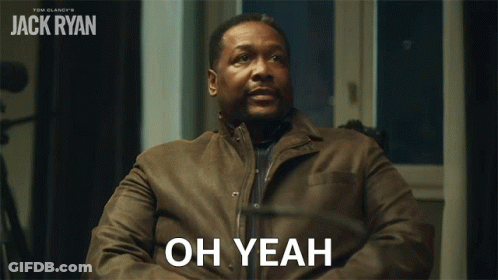 A Man In A Brown Jacket Is Sitting In Front Of A Sign That Says " Oh Yeah " GIF