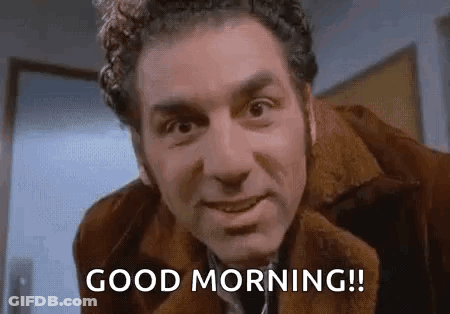A Man In A Brown Jacket Is Smiling And Says `` Good Morning '' . GIF