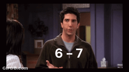 A Man In A Brown Jacket Is Talking To A Woman In A Room With The Number 6 And 7 Written On The Screen GIF