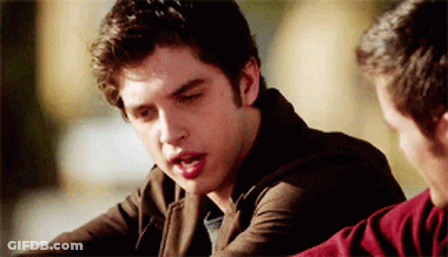 A Man In A Brown Jacket Is Talking To Another Man In A Red Sweater GIF