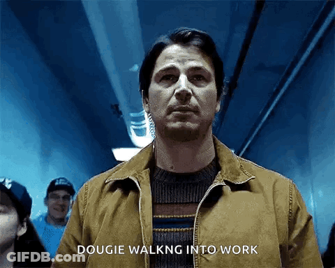 A Man In A Brown Jacket Is Walking Into A Dark Room . GIF