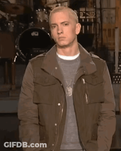 A Man In A Brown Jacket Stands In Front Of A Drum Set That Says Dw GIF