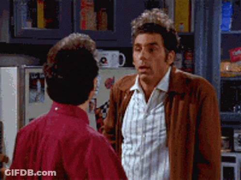 A Man In A Brown Jacket Talks To Another Man In A Kitchen GIF