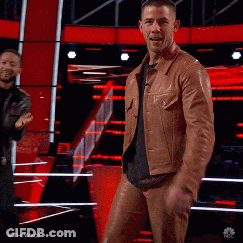 A Man In A Brown Leather Jacket And Pants Is Dancing On Stage GIF