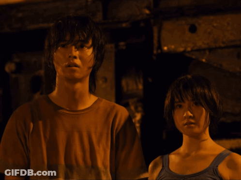 A Man In A Brown Shirt And A Woman In A Blue Tank Top Are Standing Next To Each Other GIF