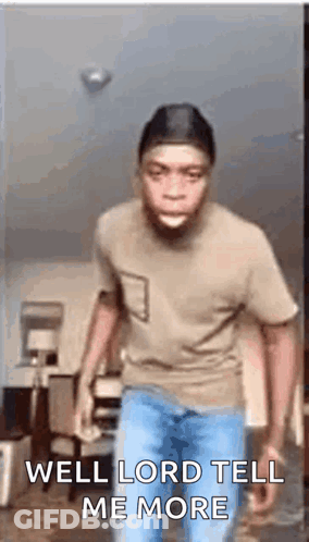 A Man In A Brown Shirt And Blue Jeans Is Standing In A Living Room . GIF