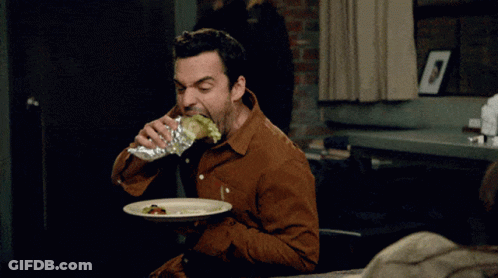 A Man In A Brown Shirt Is Eating A Sandwich And Drinking From A Bottle GIF