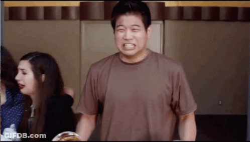 A Man In A Brown Shirt Is Making A Face GIF