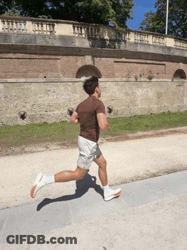 A Man In A Brown Shirt Is Running On A Road GIF