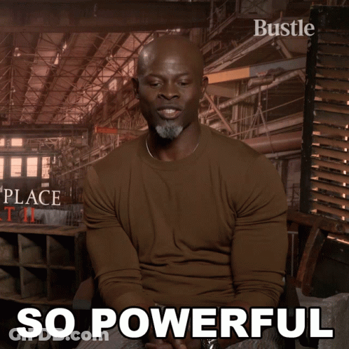 A Man In A Brown Shirt Is Sitting In Front Of A Poster That Says " So Powerful " GIF
