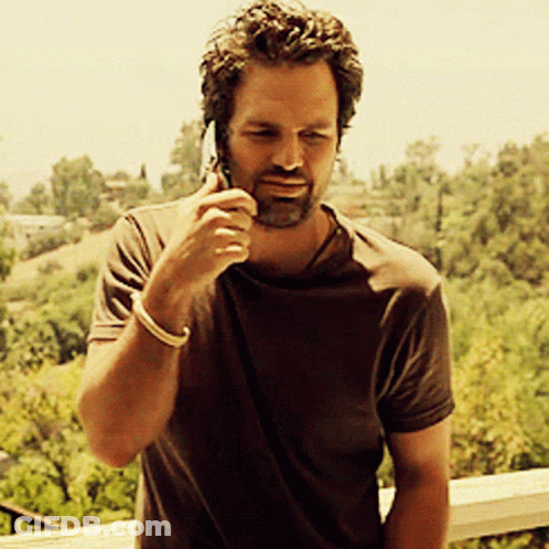 A Man In A Brown Shirt Is Talking On His Cell Phone GIF
