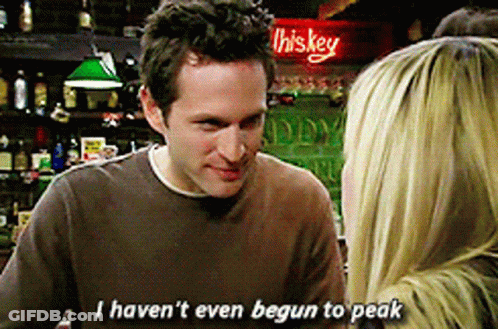 A Man In A Brown Shirt Is Talking To A Woman In Front Of A Sign That Says Whiskey GIF