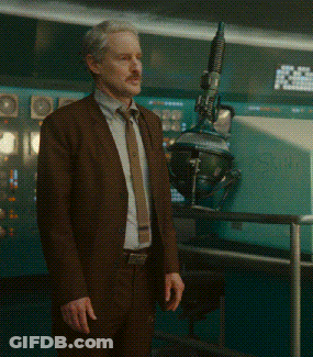 Man In Brown Suit Standing In Front Of Machine GIF